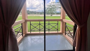 Un balcón con vista a un campo cubierto de hierba y un árbol.
