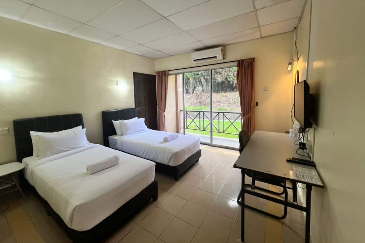 A hotel room with two beds, a desk, a television, and a sliding glass door to the outside.