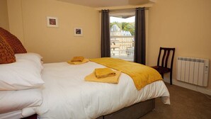 Ein Hotelzimmer mit Bett, Stuhl, Heizkörper und einem Fenster mit Vorhängen.