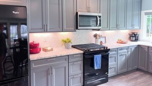 Una cocina moderna con armarios grises, un refrigerador negro, un microondas, una estufa y una cafetera.