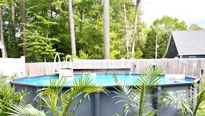 Una piscina con cubierta de madera y un cerco de madera al fondo.