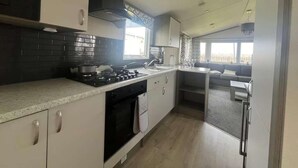 Kompakti keittiö, jossa on kaasuliesi, uuni ja modernit keittiökaapit.