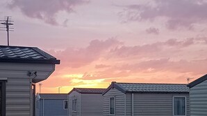 Rivi siirrettäviä taloja, joiden edessä on sorapolkua, ja taivaalla näkyy auringonlasku.