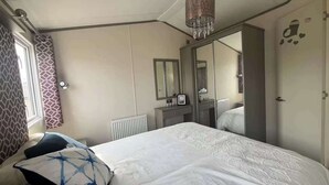 Makuuhuoneessa on suuri sänky, peili, patteri ja ikkuna, jossa on kuviolliset verhot.