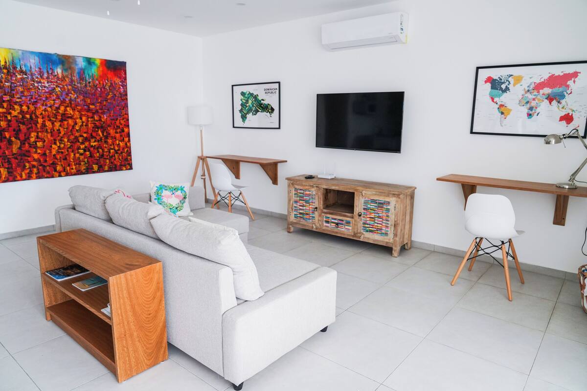 A modern living room with a sofa, coffee table, TV, and artwork on the walls.