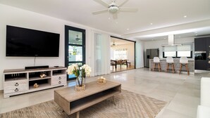 A modern living room with a flat-screen TV, wooden coffee table, and a dining area with a chandelier. - Stella Apart-hotel Las Terrenas (Las Terrenas)