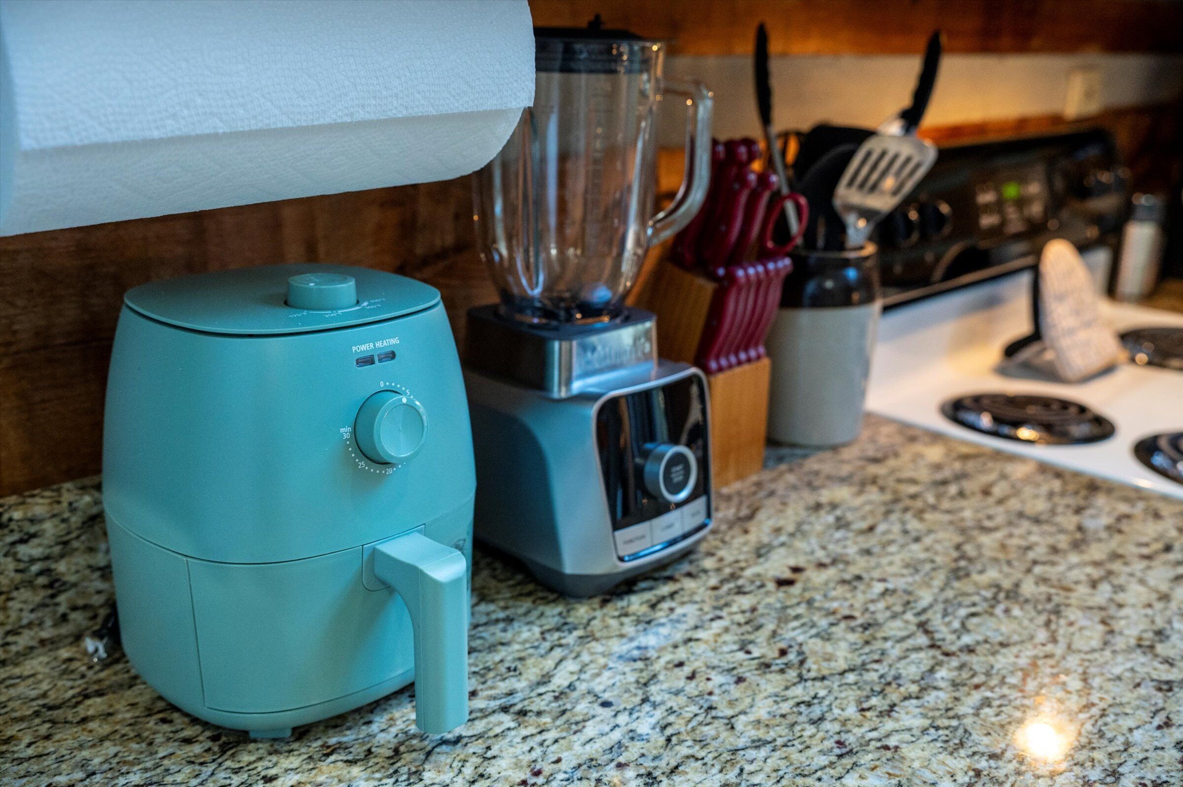 A kitchen with a blender, a toaster, and a stove.