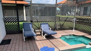 Un espace piscine avec deux chaises longues et une serviette bleue posée sur le bord.