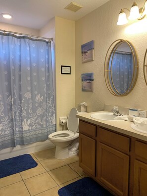 Un baño con inodoro, lavamanos y cortina de ducha.