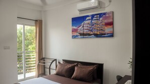 Une chambre d’hôtel avec un lit, un tableau représentant un voilier, une fenêtre avec des rideaux et un appareil de climatisation.