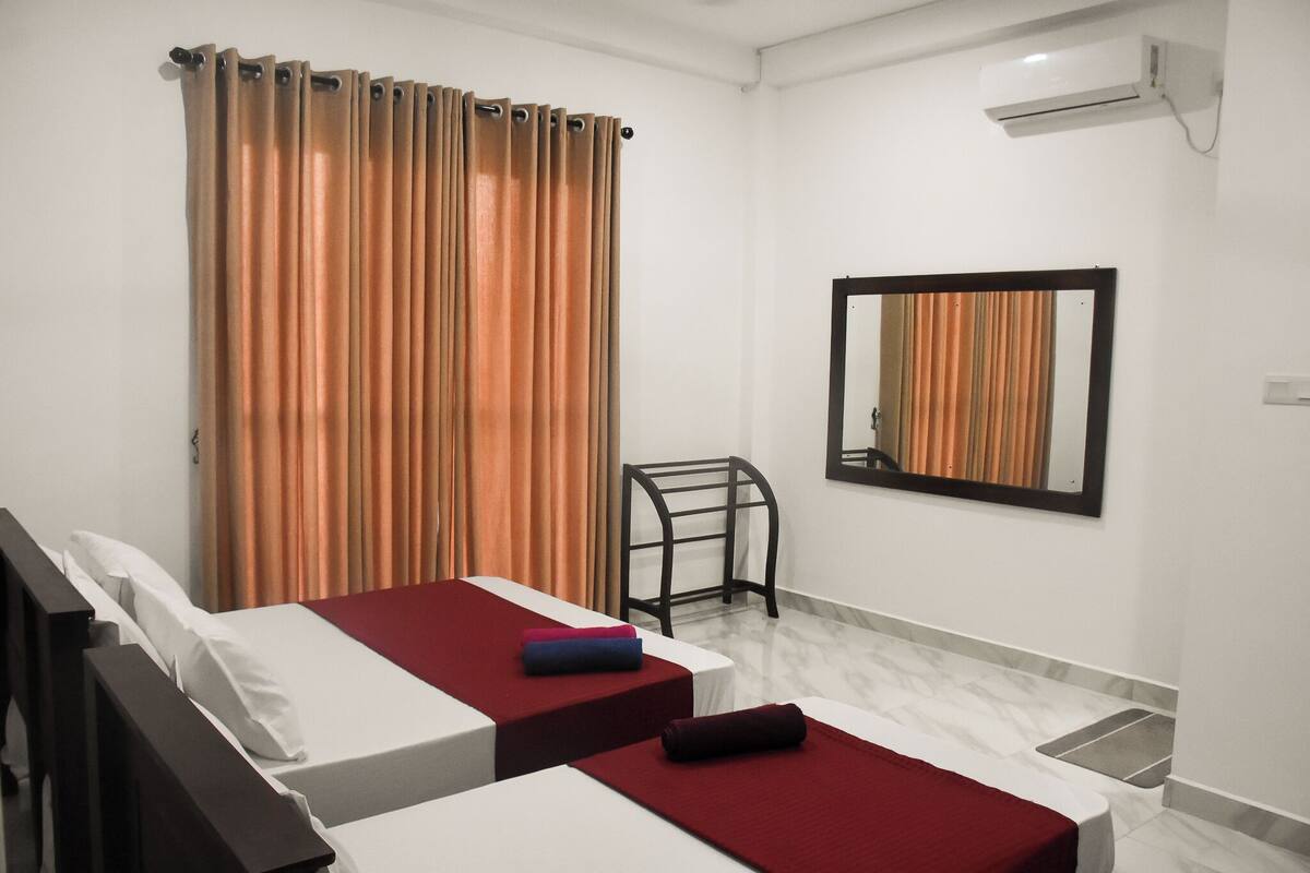 Quarto de hotel com duas camas, um espelho e um ar condicionado.