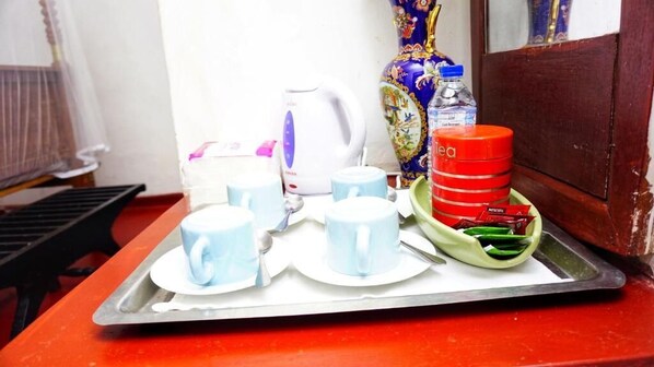 A tray with cups, a kettle, a water bottle, and a decorative vase on a table. - Habarana INN (Habarana)