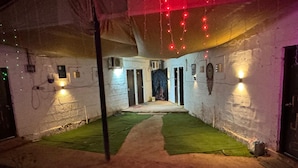 An indoor corridor with a green carpet, white walls, and red string lights. - Khushi Resort Pernem (Mandrem)