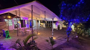 A tented outdoor area with tables and chairs, string lights, and potted plants. - Khushi Resort Pernem (Mandrem)