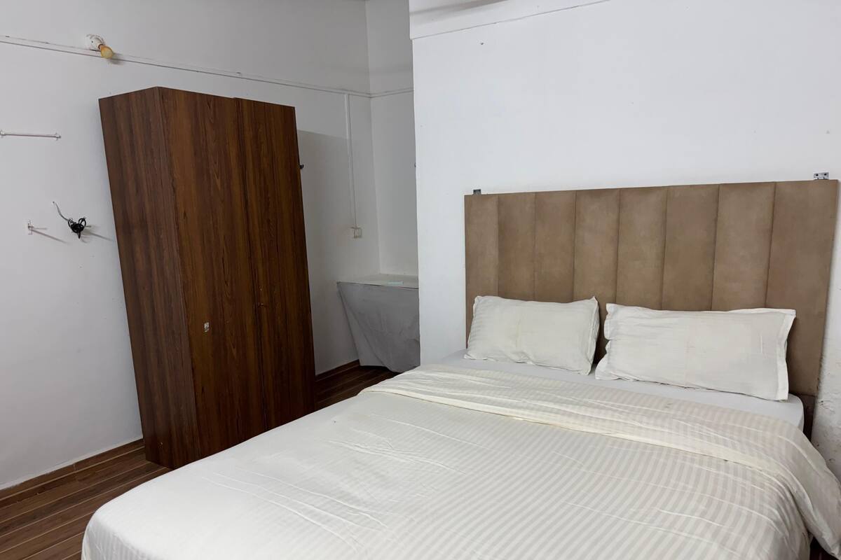 A bedroom with a bed, wooden wardrobe, and a headboard.
