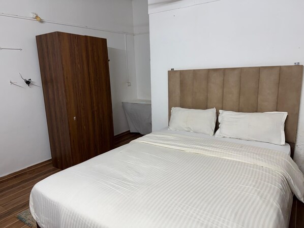 A bedroom with a bed, wooden wardrobe, and a headboard. - Khushi Resort Pernem (Mandrem)