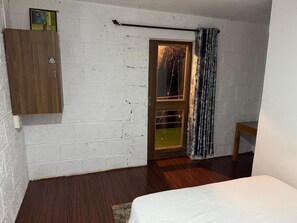 A room with a wooden wardrobe, a door with a curtain, and a bed. - Khushi Resort Pernem (Mandrem)