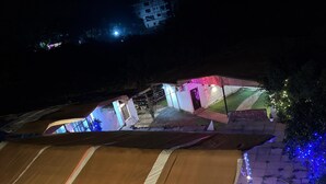 A tented outdoor area with a paved walkway, a small building with colorful lights, and a Christmas tree. - Khushi Resort Pernem (Mandrem)