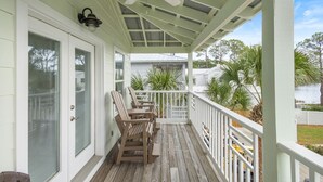 Une véranda couverte avec des chaises en bois, un ventilateur de plafond et une vue sur les environs.