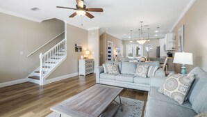 Un salon spacieux avec un plancher en bois, un canapé bleu clair, une table basse et un ventilateur de plafond.