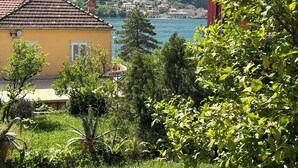 A yellow building with a tiled roof, surrounded by greenery and overlooking a body of water with other buildings in the distance. - Spacious 3 apartment , villa with WiFi and AC in delightful Dobrota (Dobrota)