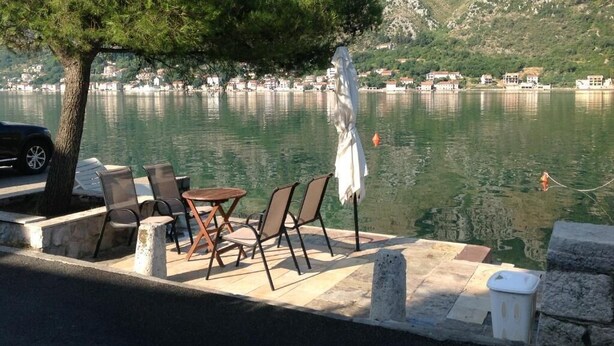 A lakeside seating area with chairs and a table, overlooking a calm lake and a mountainous backdrop. - Spacious 3 apartment , villa with WiFi and AC in delightful Dobrota (Dobrota)