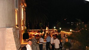An outdoor dining area with tables and chairs, surrounded by a brick wall and palm trees. - Spacious 3 apartment , villa with WiFi and AC in delightful Dobrota (Dobrota)
