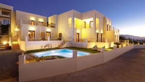 A modern multi-story hotel with a swimming pool, outdoor seating, and balconies. - Green A Seaside Escape With Mesmerizing Views (Rethymno)
