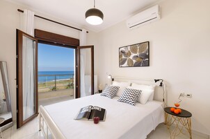 Un dormitorio con cama, una mesita de noche, ventana con vistas al mar y aire acondicionado.