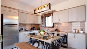 Uma cozinha moderna com eletrodomésticos de aço inoxidável, uma mesa de jantar de madeira e cadeiras pretas.