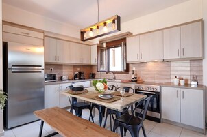 Una cocina moderna con electrodomésticos de acero inoxidable, una mesa de comedor de madera y sillas negras.