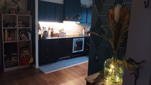 A modern kitchen with dark blue cabinets, a built-in oven, and a countertop with various kitchen items. - Large, cosy house near the town center (Nantes)