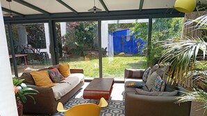A spacious living area with a large glass door leading to a garden, furnished with sofas and a coffee table. - Large, cosy house near the town center (Nantes)