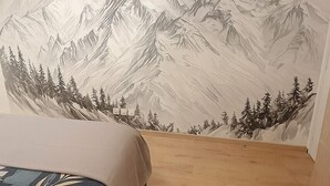 Une chambre à coucher avec un lit, un plancher en bois et une fresque murale représentant des montagnes et des arbres.