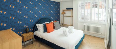 Une chambre à coucher avec un lit, une table de chevet en bois et une fenêtre avec des stores.