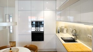 A modern kitchen with white cabinetry, a built-in oven, a stainless steel range, and a wooden countertop. - CA.Tanoeiros 2 (Funchal)