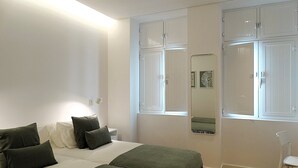 A bedroom with two beds, a nightstand, a mirror, and a chair. - CA.Tanoeiros 2 (Funchal)