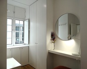 Modern bathroom with a white vanity, round mirror, and natural light from the window.