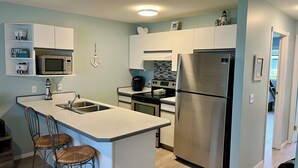 A modern kitchen with a central island, stainless steel appliances, and a small dining area with two chairs. - Sicamous Townhouse & Boat Slip. Welcome to the lake! (Sicamous)