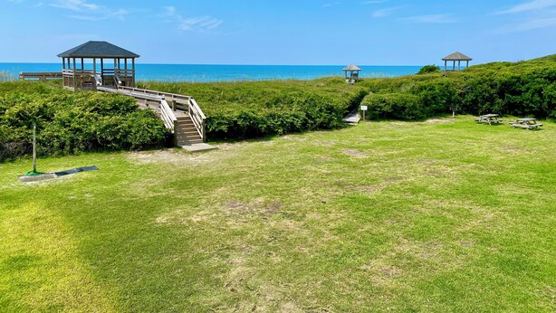 A beachside property with a gazebo, a wooden staircase, and picnic tables.