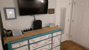 A room with a teal and white dresser, a flat-screen TV mounted on the wall, and a door with a 'KEYS' sign.