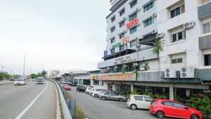 Ένα πολυώροφο ξενοδοχείο με μια μεγάλη, εμφανή επιγραφή «OYO», μια επιγραφή «HOTEL 75» και μια επιγραφή «PUSAT SNKER».