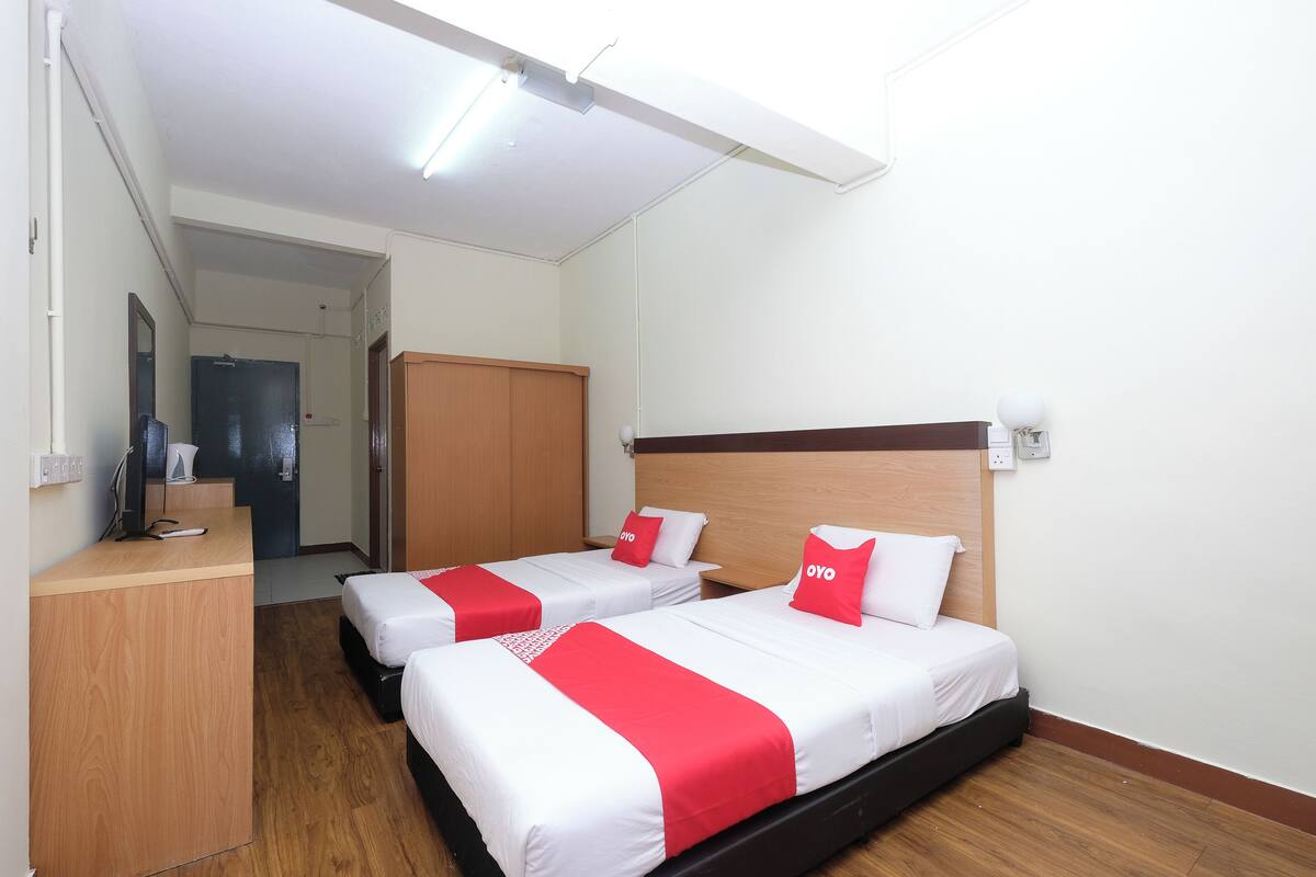 A hotel room with two beds, a wooden desk, and a mirror.