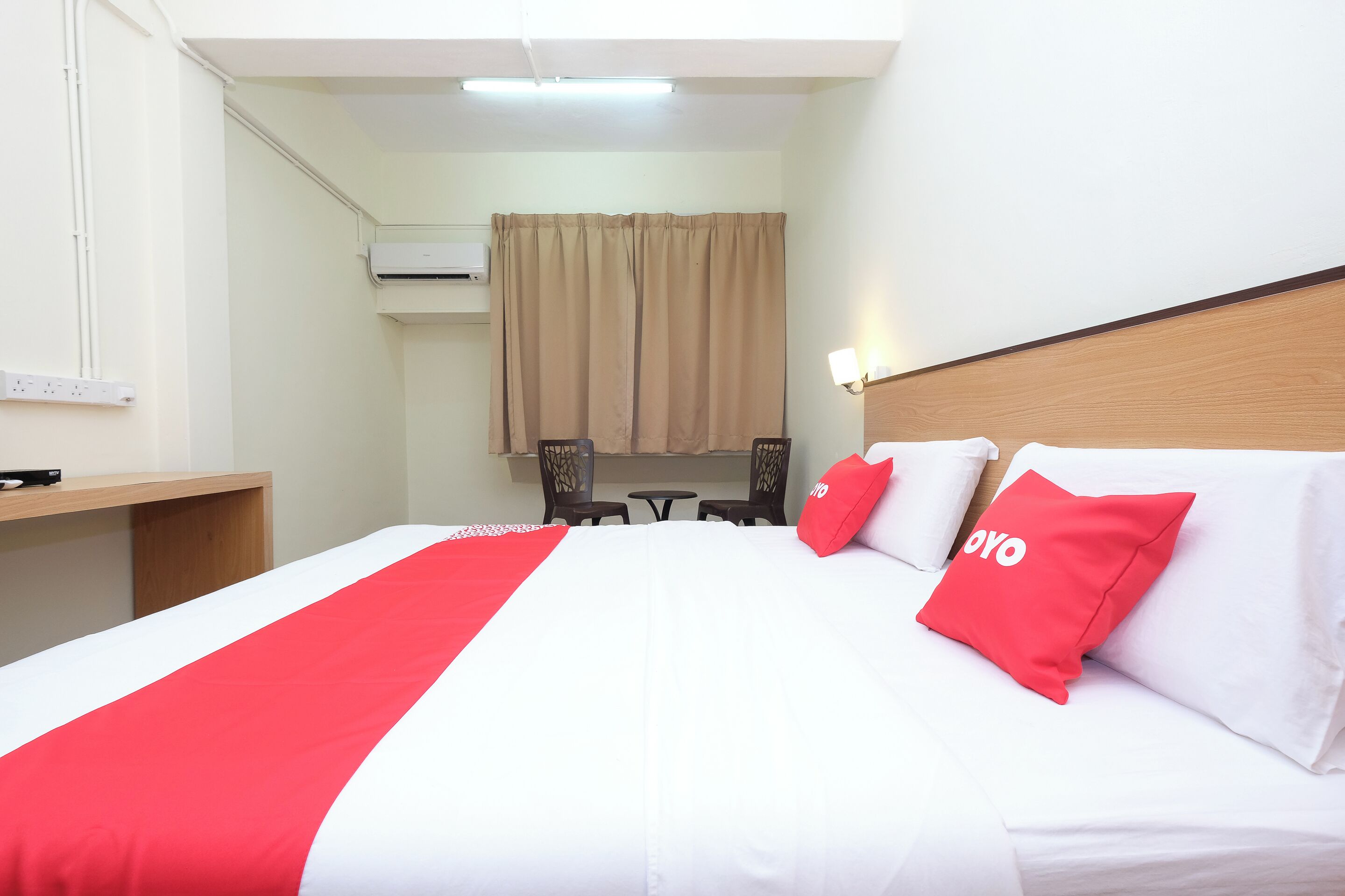 Une chambre d’hôtel avec un lit, un bureau et une petite table avec des chaises.
