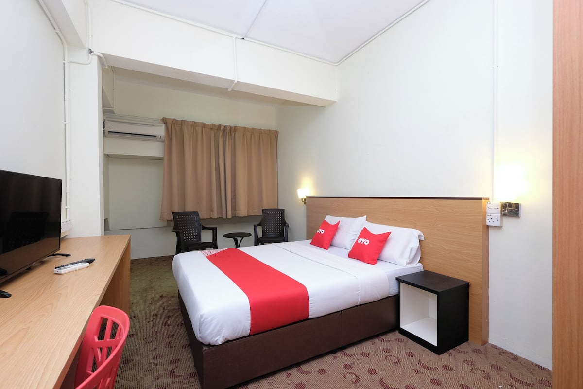 A hotel room with a bed, a desk, a TV, and a chair.