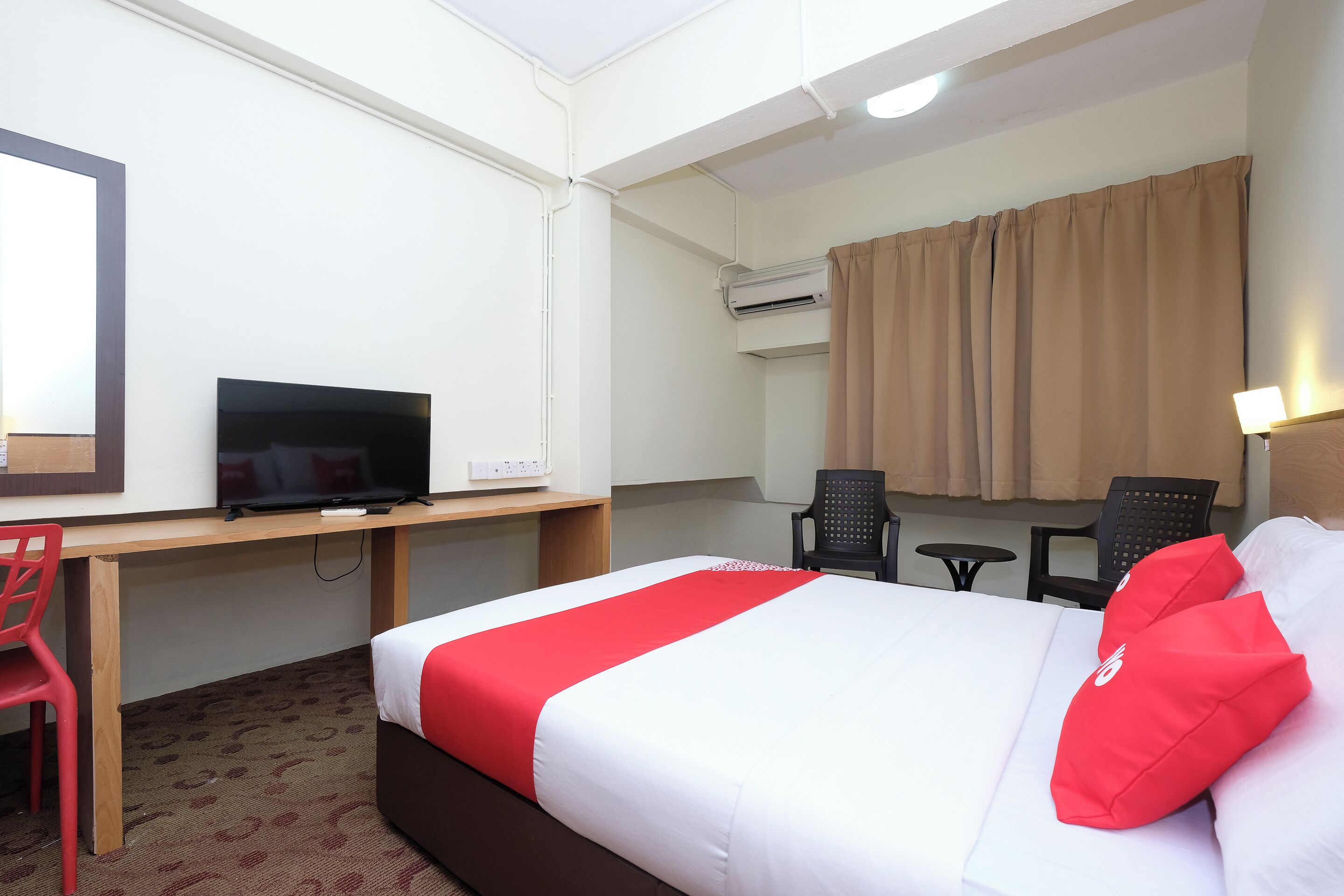 Une chambre d’hôtel comprenant un lit, un bureau avec une télévision, une chaise et un appareil de climatisation.