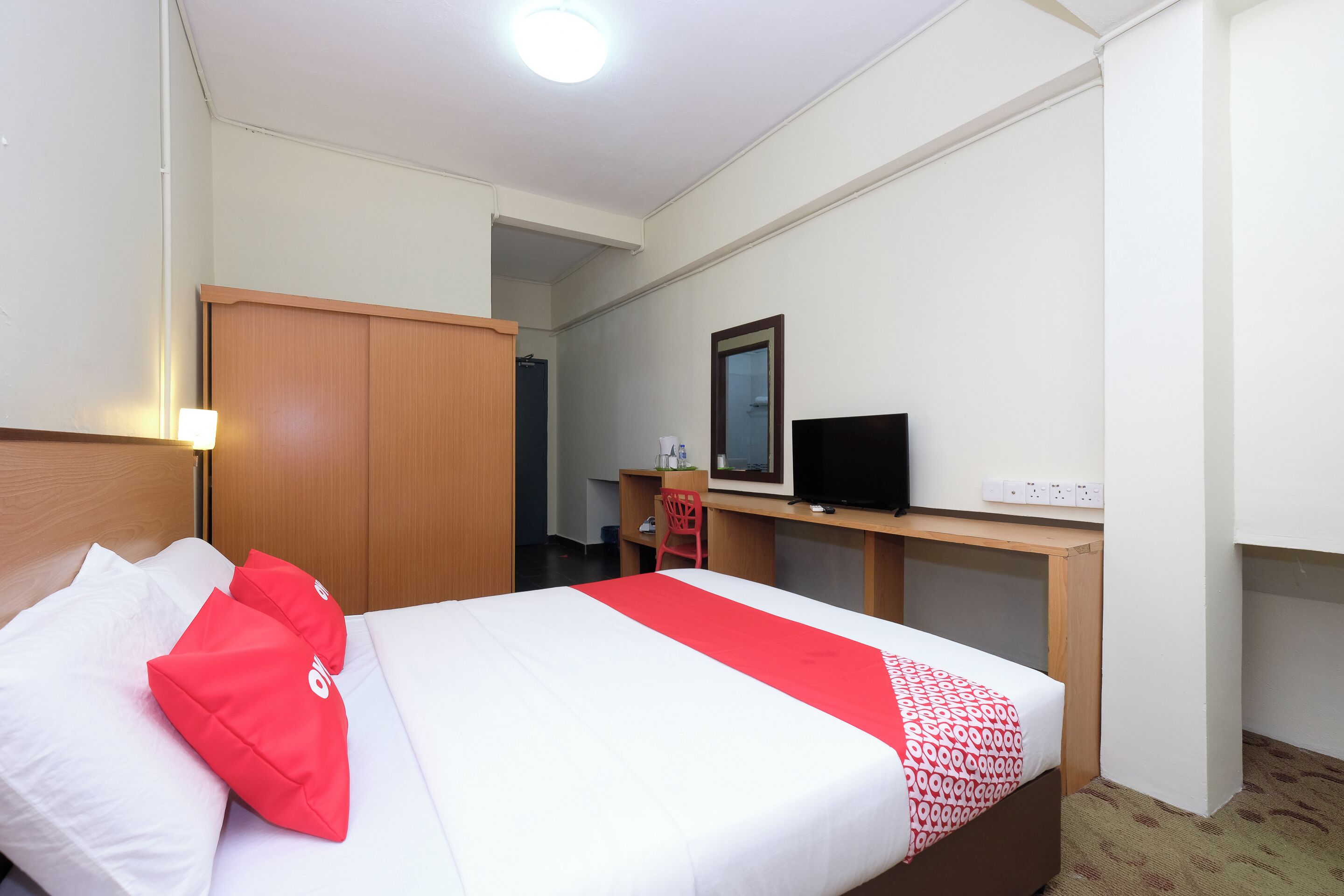 Una habitación de hotel con cama, escritorio, televisión y armario.