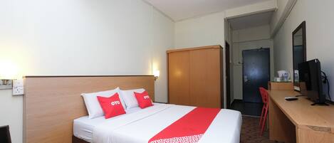 A hotel room with a bed, a desk, a chair, and a wardrobe.