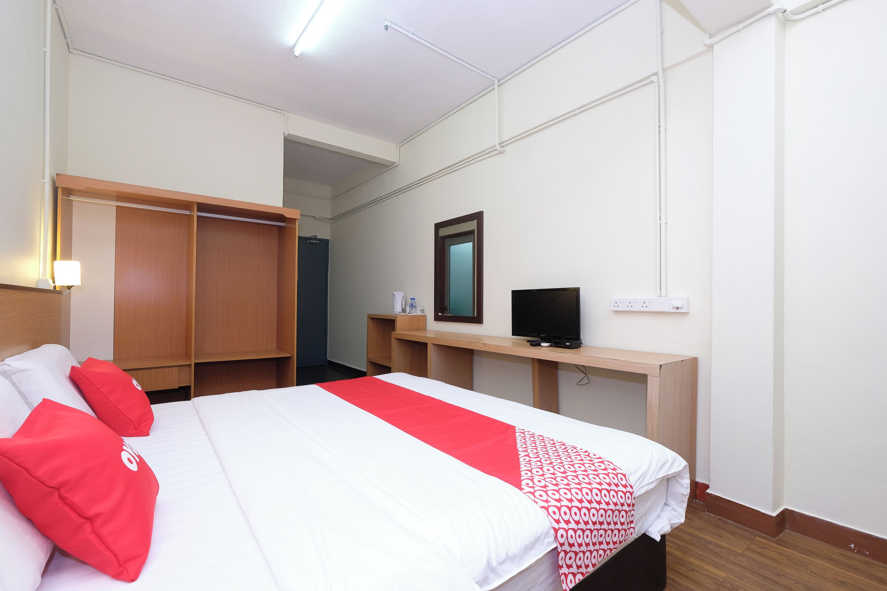 A hotel room with a bed, a TV, a desk, and a wardrobe.