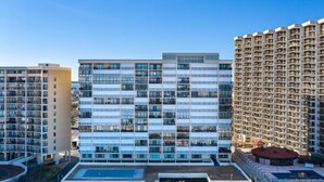 A modern multi-story building with a central courtyard, balconies, and a pool area. - Cozy Studio l Oceanfront l Pool l WiFi (Ocean City)